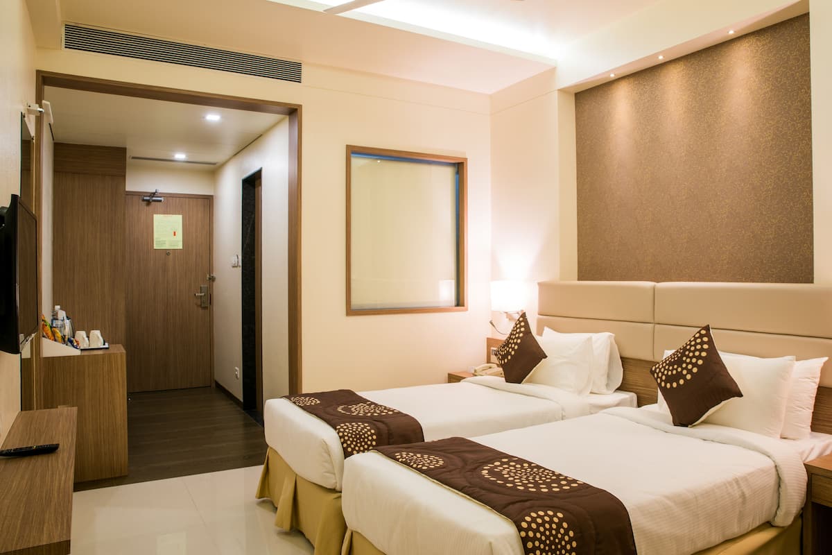 A hotel room with two beds, a desk, and a mirror.