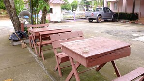 Outdoor picnic tables with benches, a broom, and a trash bag on the ground. - Bansuannamdee (Pluak Daeng)