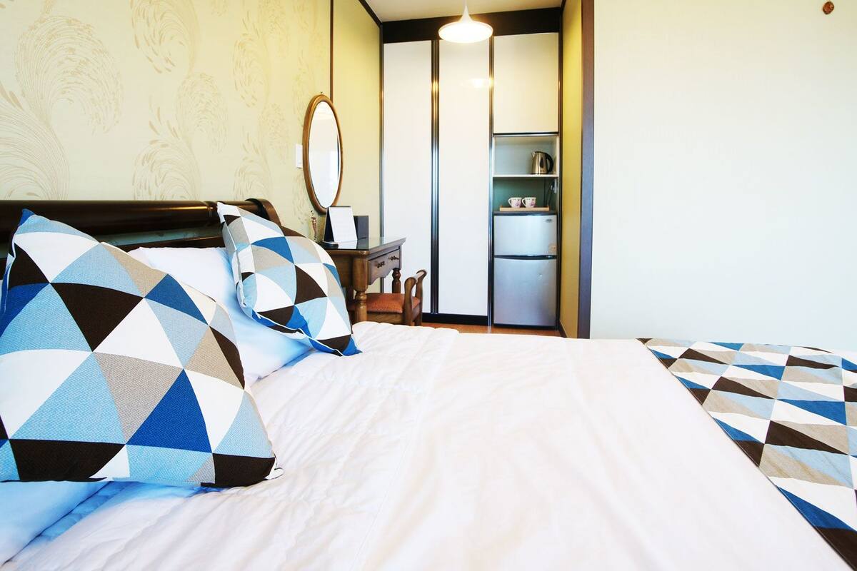 A hotel room with a bed, a desk, and a wardrobe.