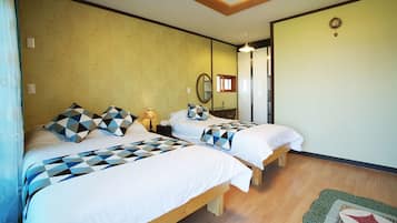 A room with two beds, each with geometric-patterned bedding, a wooden floor, and a mirror on the wall.