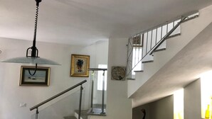 A staircase with a metal railing, a pendant light, and framed artwork on the walls. - PINE CONE DIRECT ACCESS TO THE BEACH ( NO WIFI ) CIN IT091063C2000S5156 (Cala Liberotto  Sos Alinos  (Orosei))