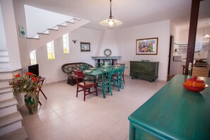 A dining area with a table and chairs, a staircase, and a kitchen area.