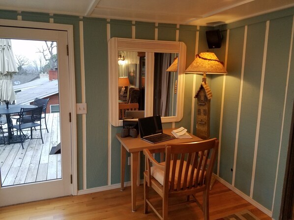 A room with a wooden desk, a laptop, and a chair. There is a window with a view of a patio and a door leading outside. - Best Views on Beaver Lake close to Rogers (Rogers)
