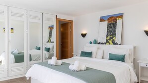 Habitación de hotel con una cama grande, un armario con puertas correderas, una mesita de noche y un cuadro en la pared.