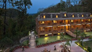 A multi-story wooden building with balconies, surrounded by a landscaped garden and a pond. - The Rangers Reserve - Corbett (Nainital)