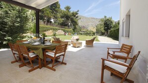 Une terrasse extérieure avec une table dressée pour le repas, entourée de chaises en bois.