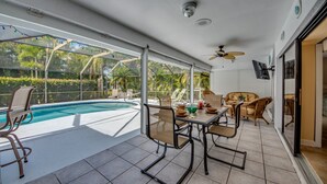 A covered outdoor area with a pool, seating, and a ceiling fan. - Villa Bonita, Located 5 Min. from Bonita Beach, WIFI, Private Lanai & Pool (Bonita Springs)