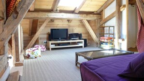 A cozy attic bedroom with a wooden ceiling, a television on a low shelf, a purple bed, and a small table. - Chalet - Samoens (Samoëns)