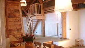 A wooden interior with a dining table, chairs, a vase with flowers, and a staircase leading to an upper level. - Chalet - Samoens (Samoëns)