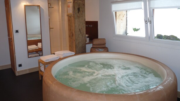 A bathroom with a large bathtub, a mirror, a towel rack, and a window. - Chalet - Samoens (Samoëns)