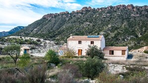 Uma casa de pedra com telhado de cerâmica, emoldurada por uma paisagem montanhosa.