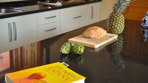 Uma bancada de cozinha com um livro intitulado 'Culinaria Espanza', uma abacaxi e alcachofras.