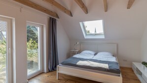 Ein Schlafzimmer mit Bett, Dachfenster, Nachttisch und Blick ins Freie.