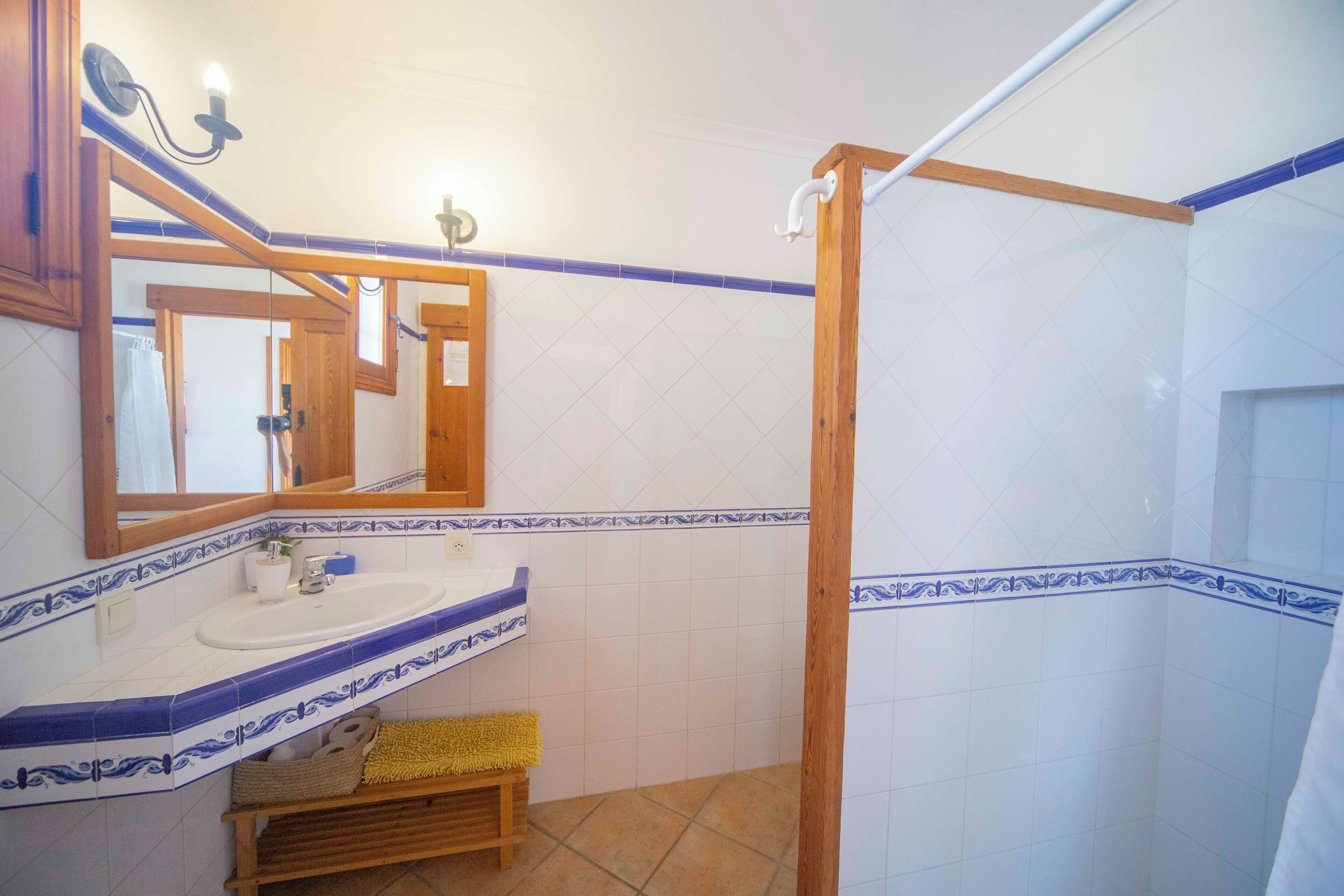 Een badkamer met een douche met houten frame, een wastafel met spiegel en blauwe betegelde wanden.