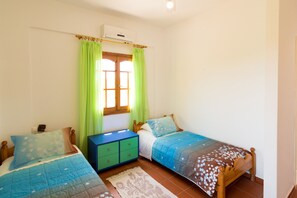 A bedroom with two beds, a dresser, and a window with curtains.