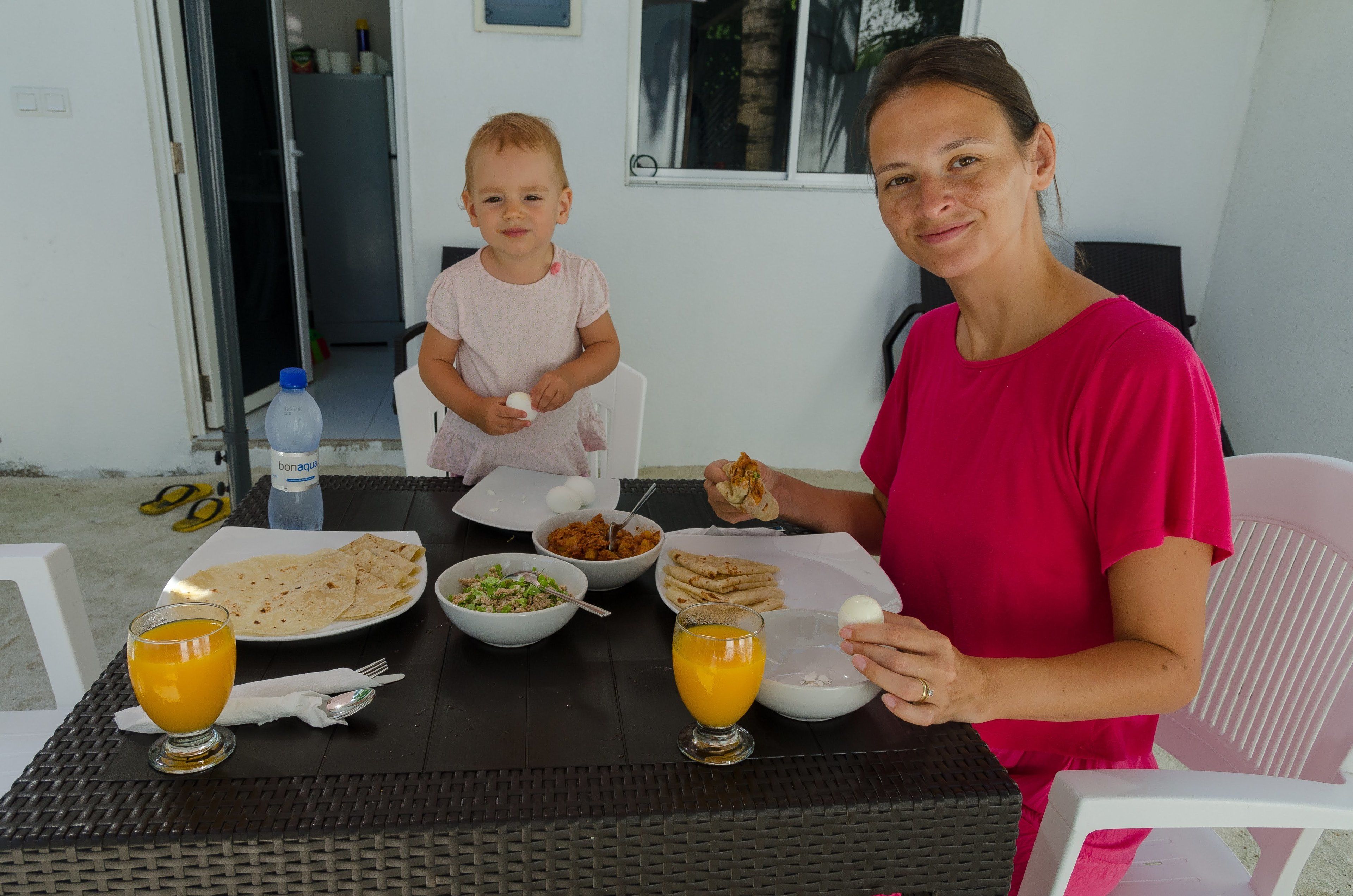 A dining table with food and drinks, a baby, and an adult.