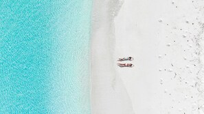 A beach with two people lying on the sand, facing the water.