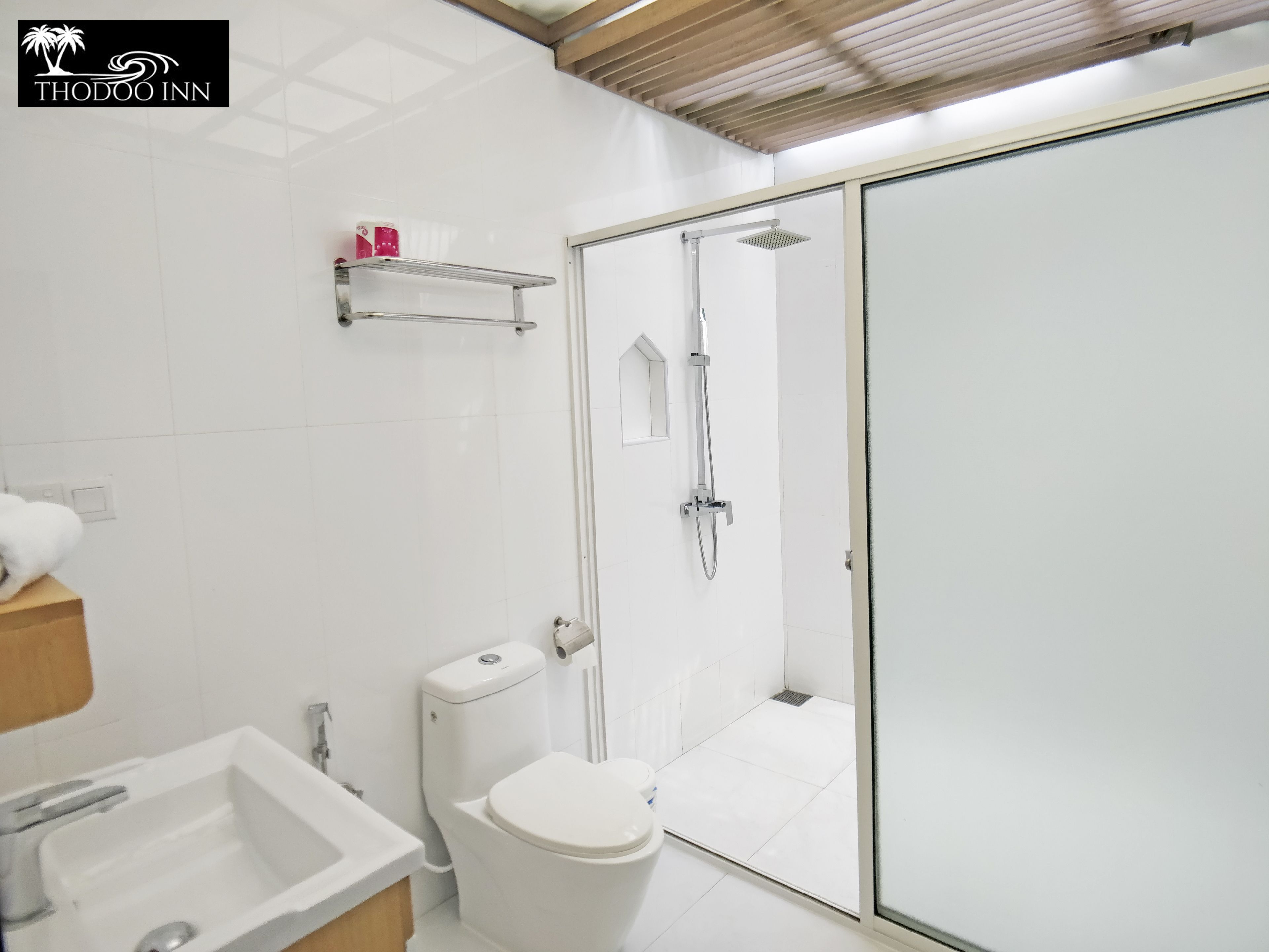 Une salle de bain moderne équipée d’une douche, de toilettes, d’un lavabo et d’une porte de douche en verre.