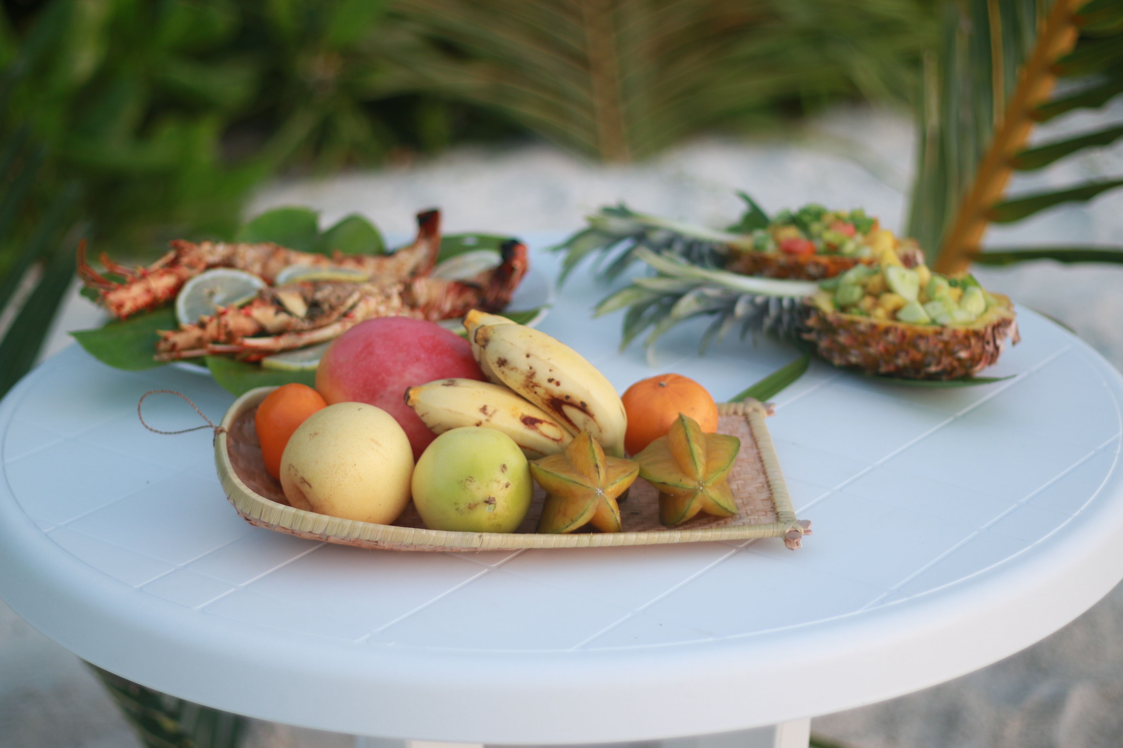 A table with a variety of fruits and a small dish of food.