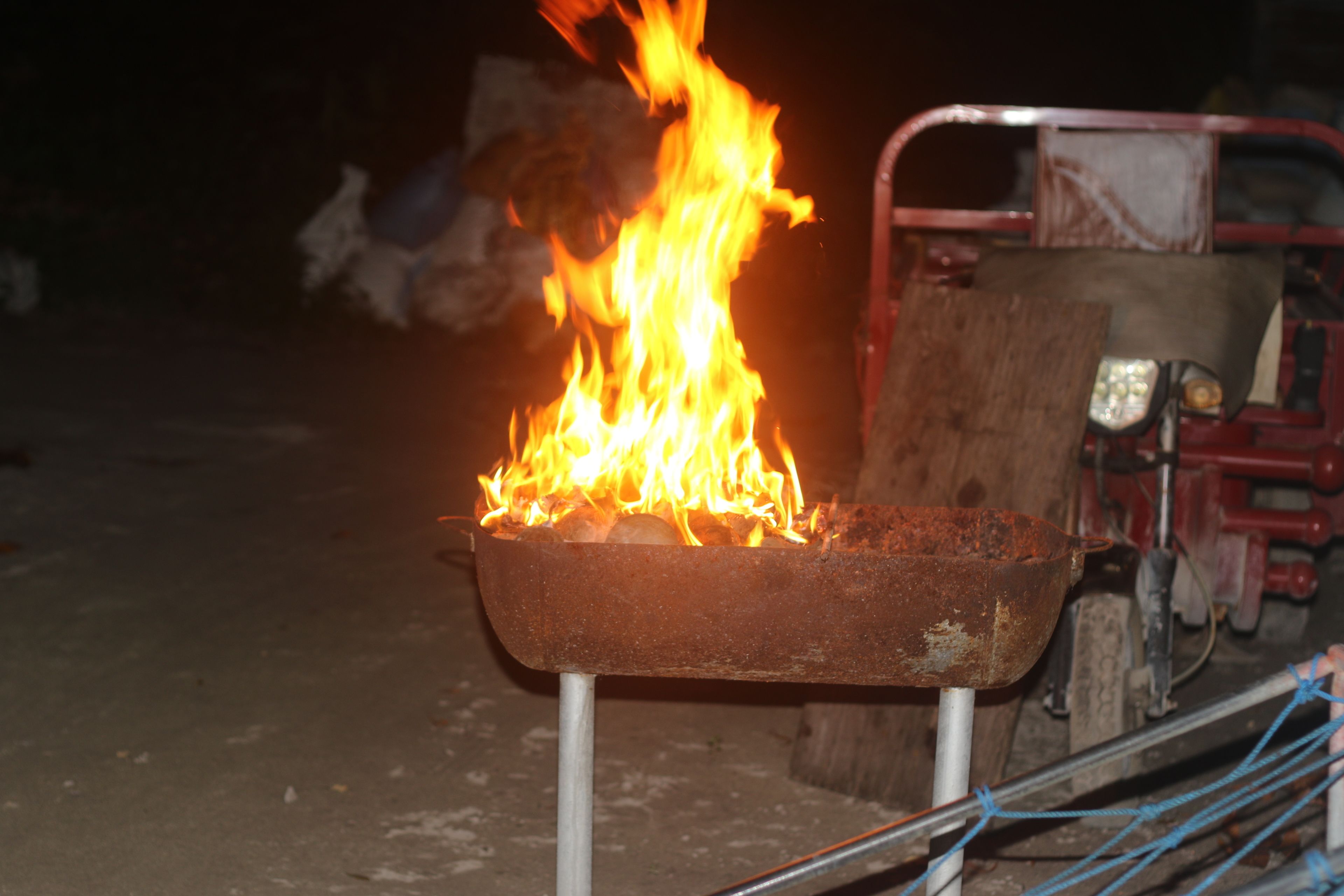A metal tray with a fire burning on it, supported by a metal stand.
