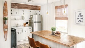 A modern kitchen with white cabinets, a wooden island, and a stainless steel refrigerator.