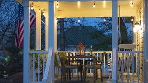 A covered porch with outdoor seating, a flag, and a lantern.