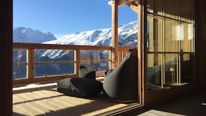 Een houten terras met uitzicht op besneeuwde bergen.