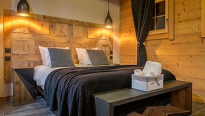 Een slaapkamer met houten lambrisering, een bed, nachtkastjes en een nachtkastje.