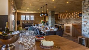 Een eethoek met een houten tafel gedekt voor een maaltijd, een grote schaal champagne en glazen.