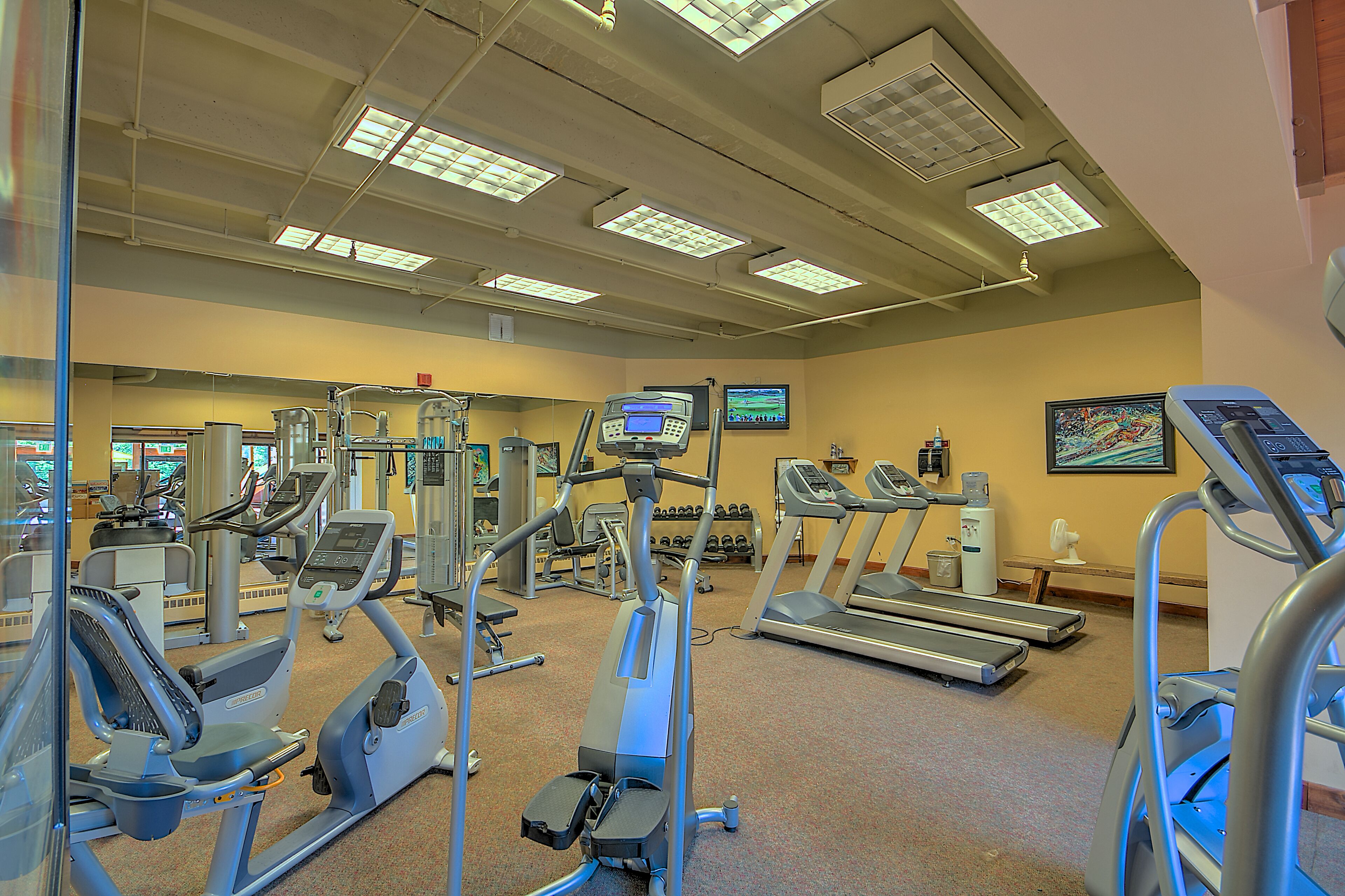 Une salle de sport équipée de divers appareils d’exercice, notamment des tapis de course et des appareils de musculation elliptique.