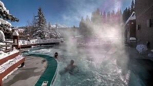 Un área de aguas termales con árboles cubiertos de nieve y cielo despejado.