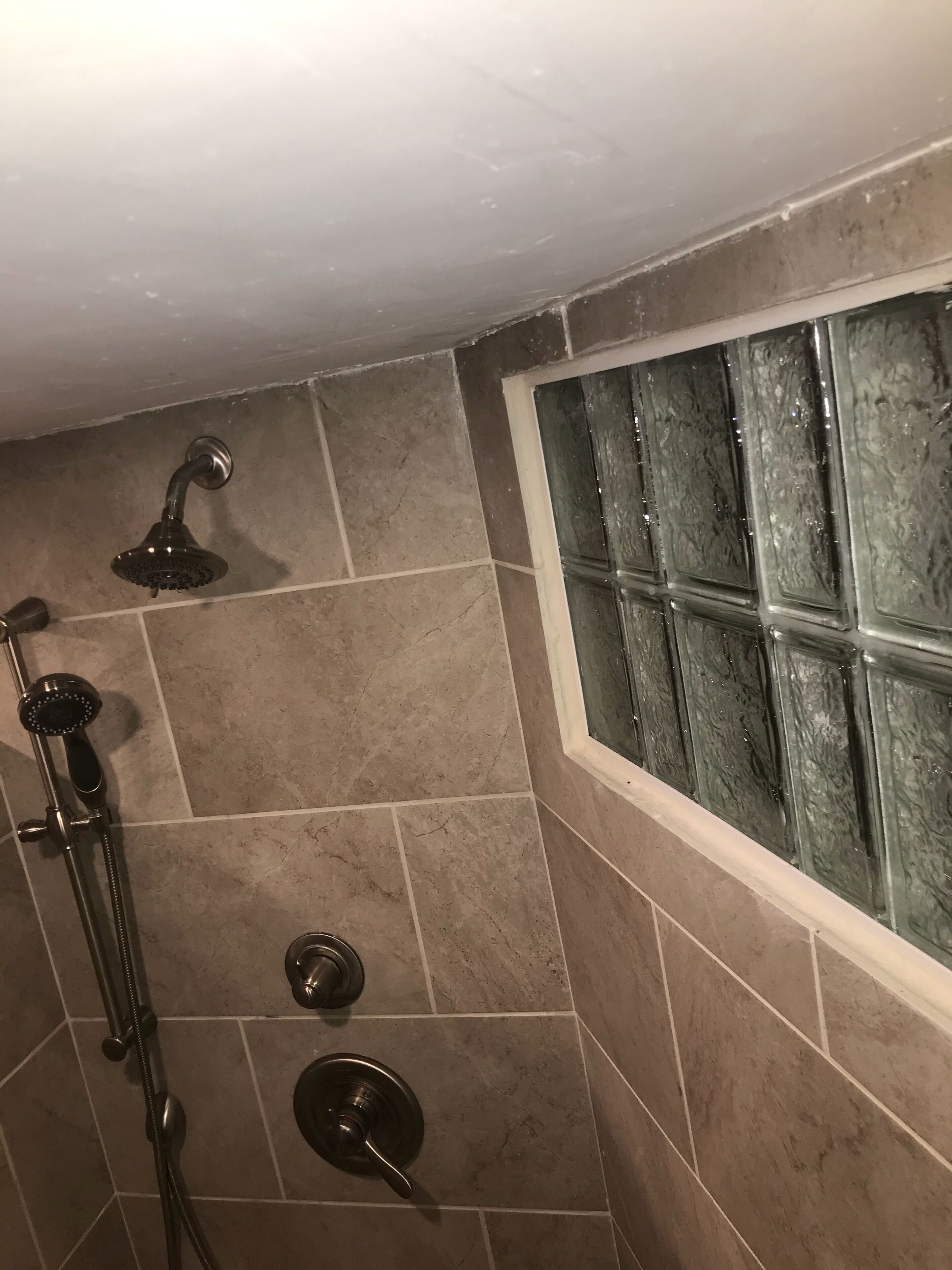 A shower area with a glass door, tiled walls, and a handheld showerhead.