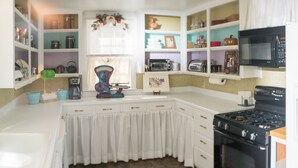 Una cocina con armarios blancos, estufa, microondas y varios electrodomésticos.