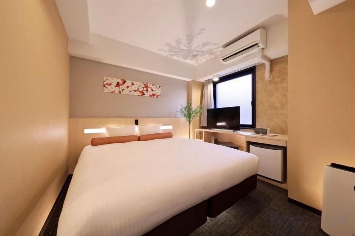 Una habitación de hotel con una cama grande, un escritorio con computadora y una televisión.