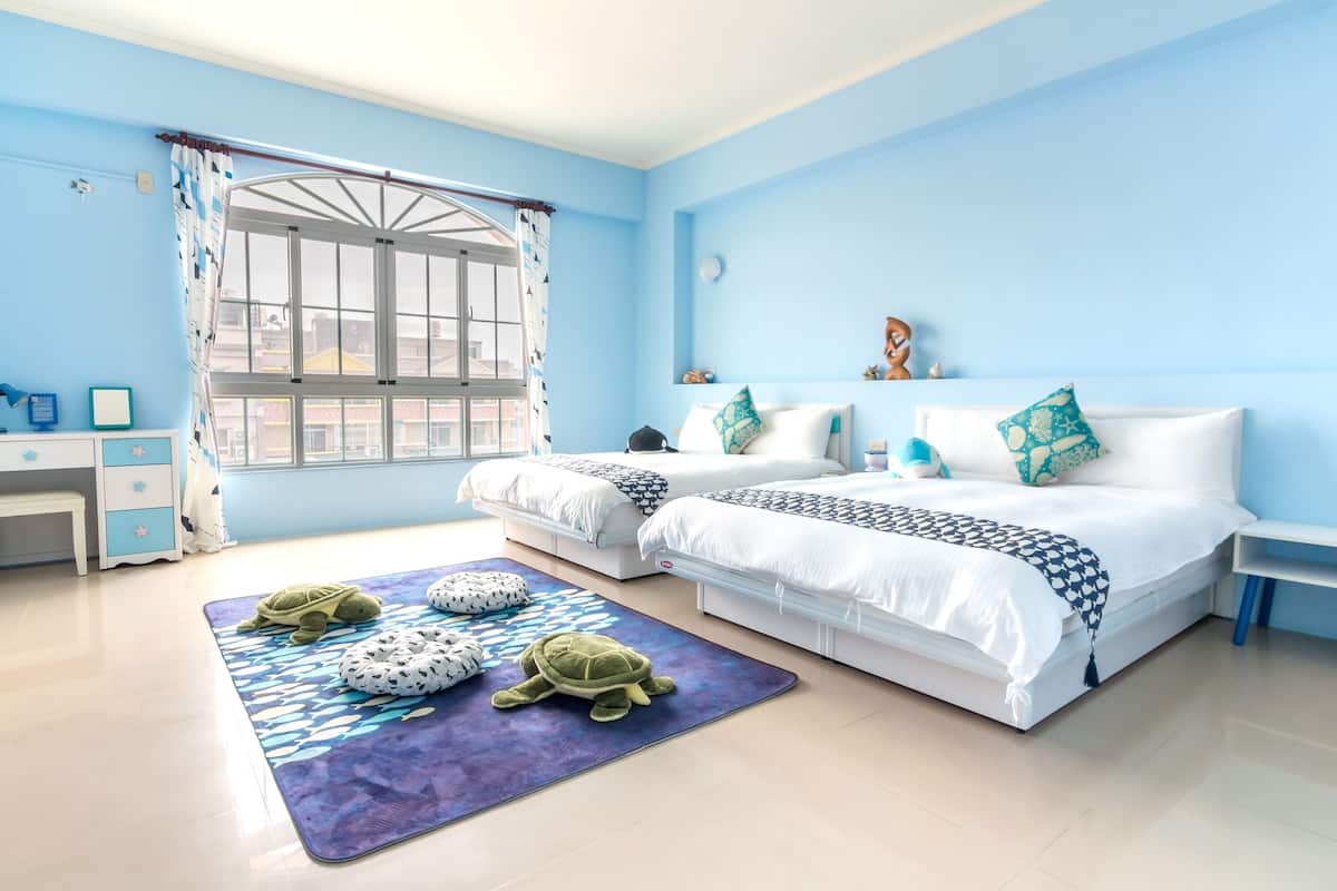 Un dormitorio con dos camas, un escritorio y una ventana con cortinas.