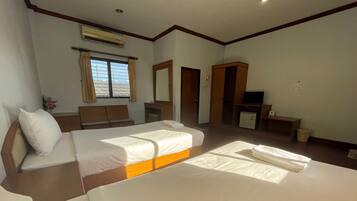 A hotel room with two beds, a desk, a TV, and an air conditioning unit.