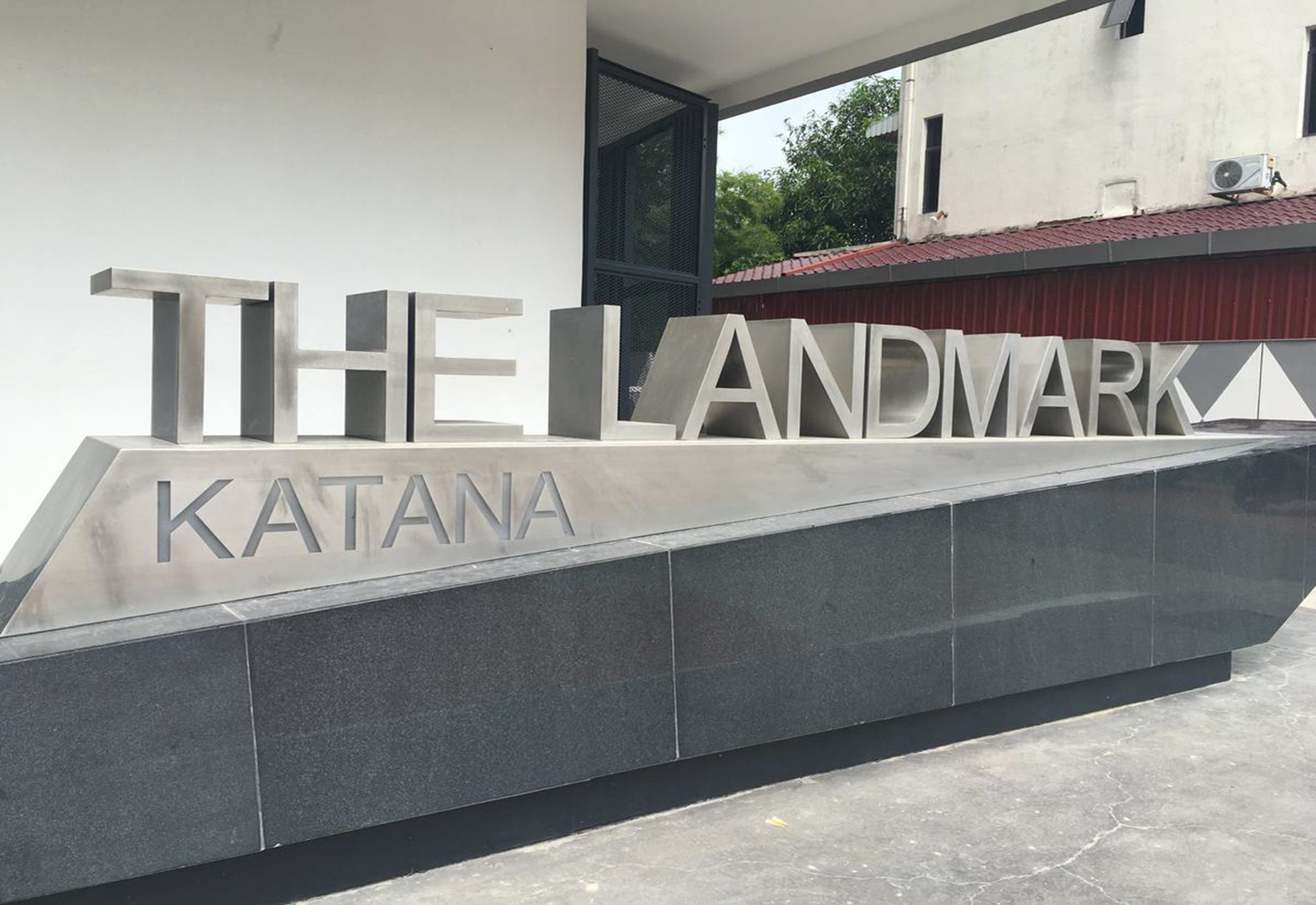Un edificio moderno con letras metálicas grandes que deletrean "THE LANDMARK" y "KATANA" en su fachada.