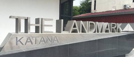 Un edificio moderno con letras metálicas grandes que deletrean "THE LANDMARK" y "KATANA" en su fachada.