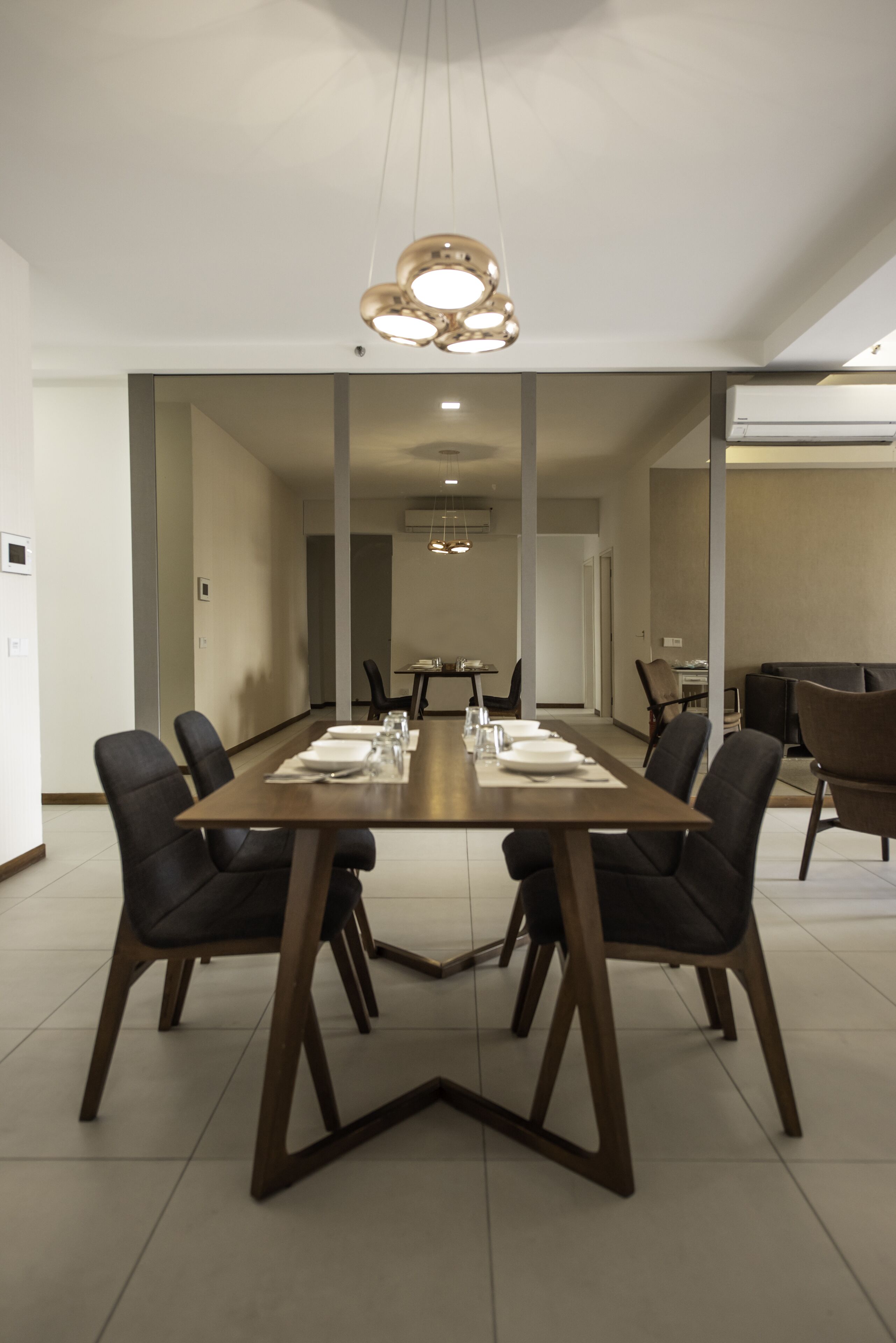 Un comedor moderno con una mesa larga, sillas negras y una lámpara de techo original.