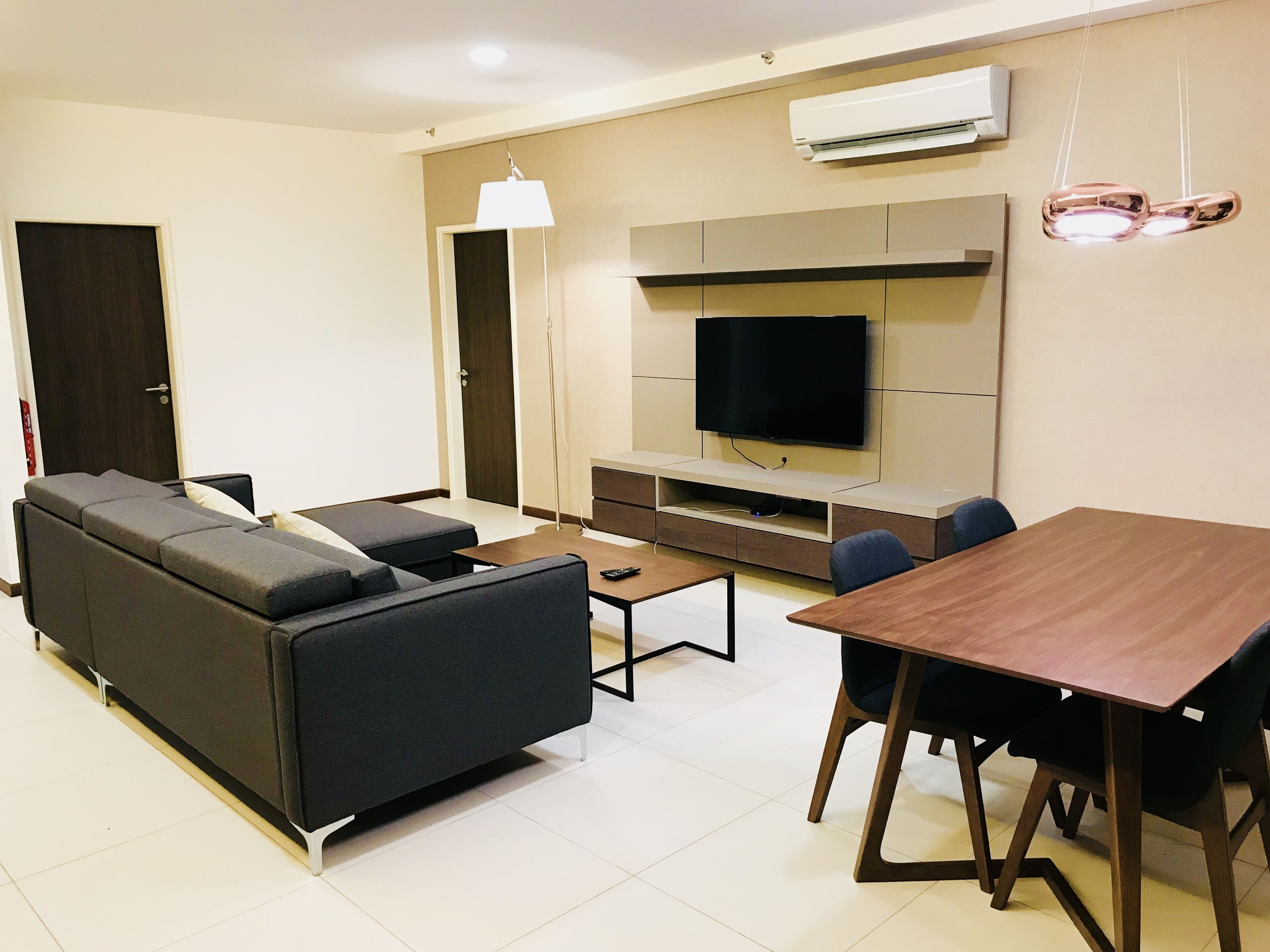 A modern living room with a sofa, a coffee table, a TV, and a dining table with chairs.