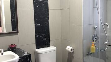 Un baño con inodoro, lavamanos y ducha.