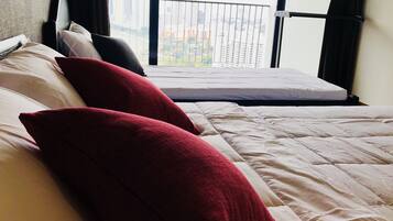A hotel room with a bed, pillows, and a view of a cityscape through a window.
