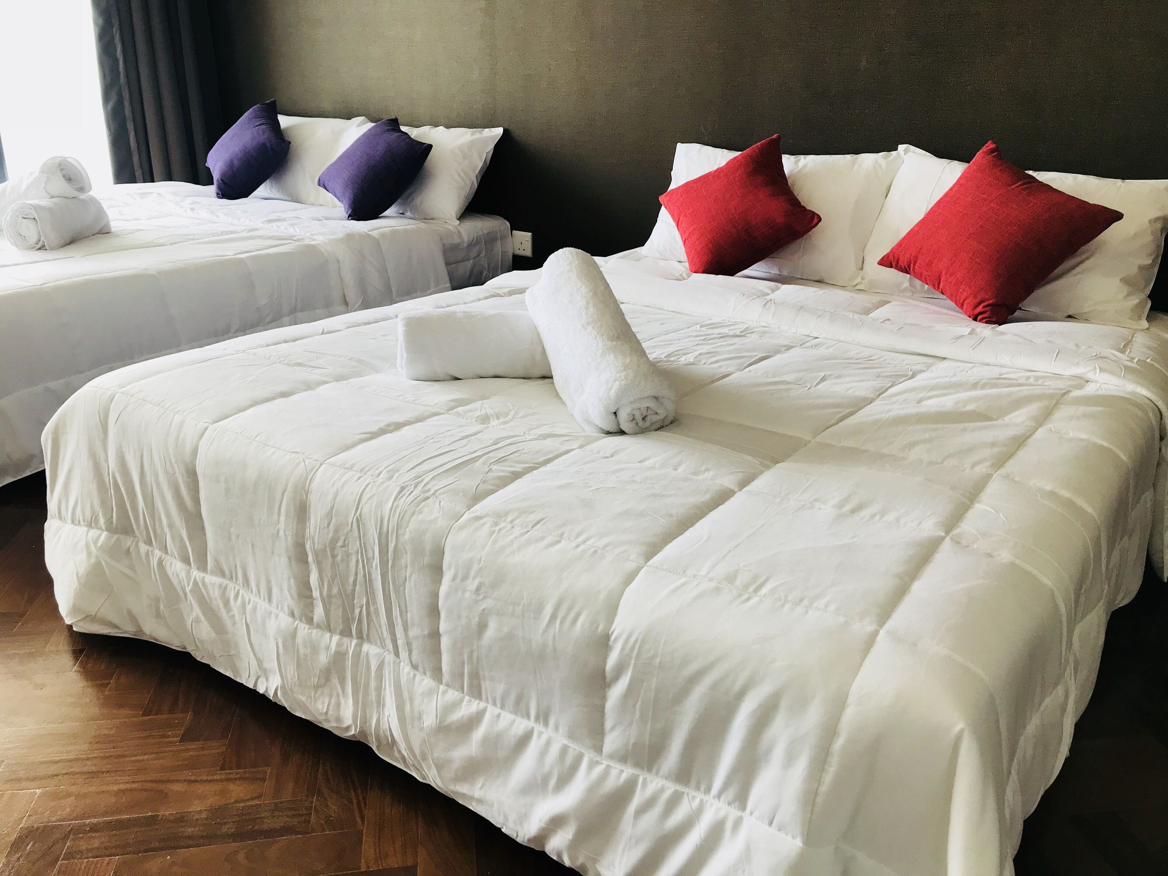 A hotel room with two beds, each with white bedding and pillows in various colors.