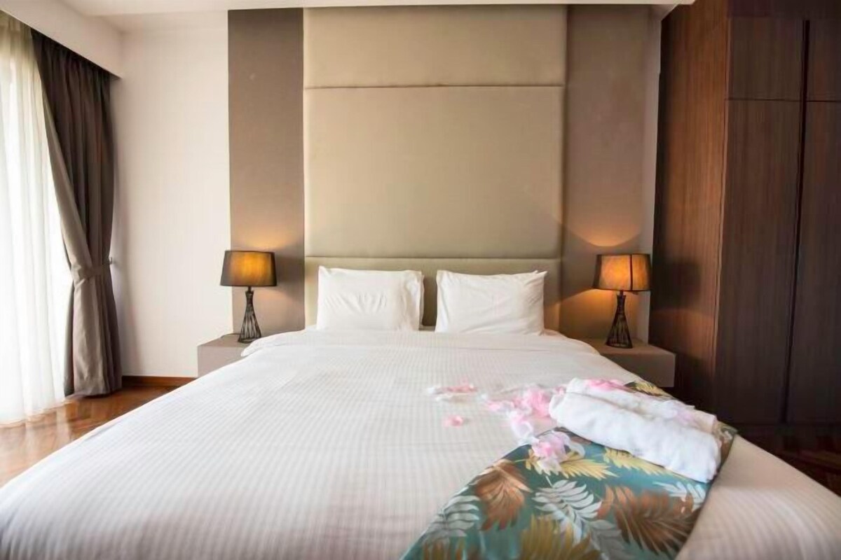 A hotel room with a large bed, two bedside lamps, a headboard, and a nightstand.