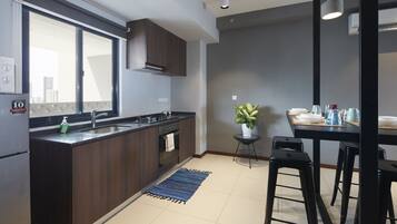 Een moderne keuken met een groot raam, donkere houten kasten, een ingebouwde oven en een zithoek met krukken.