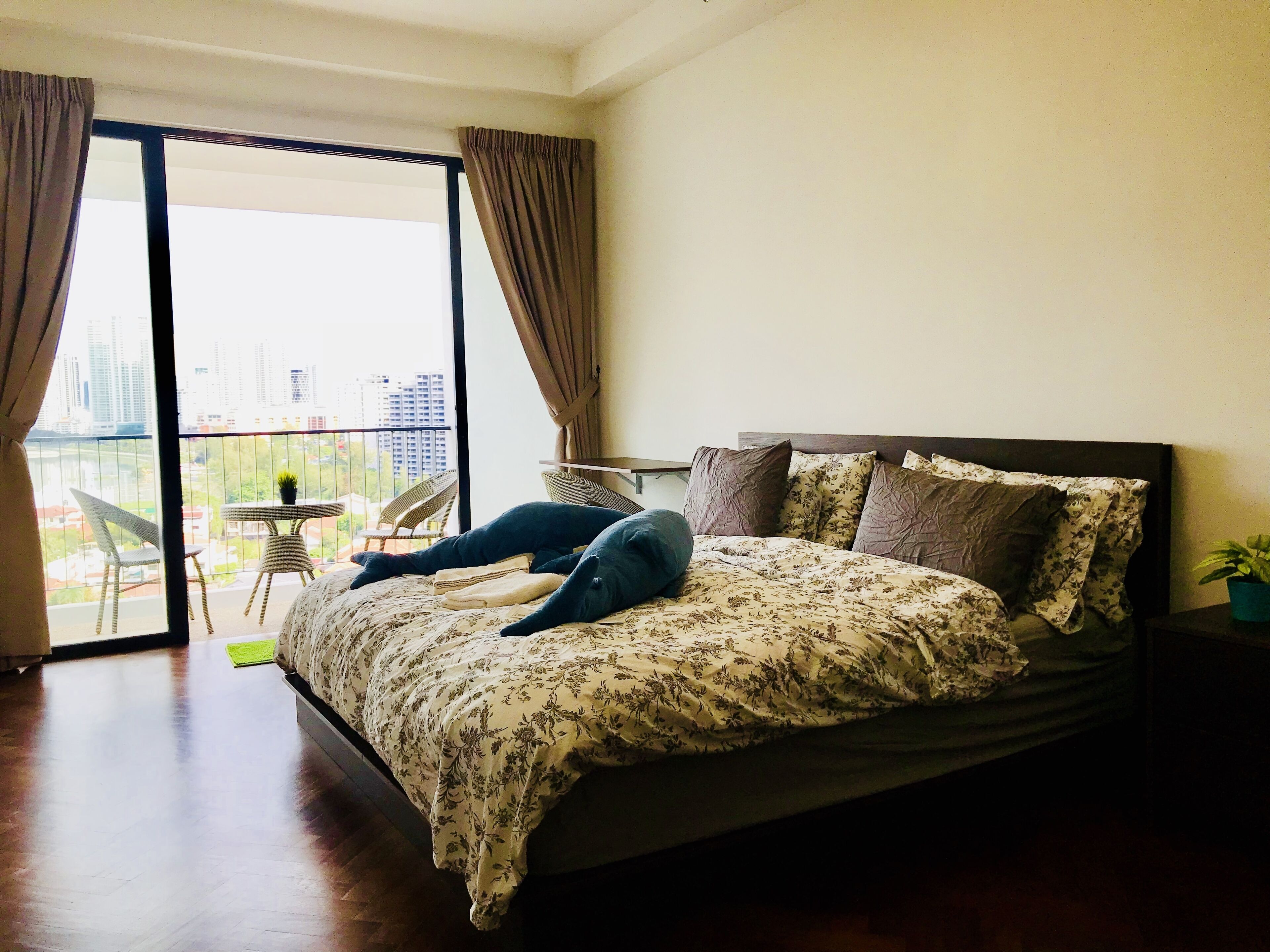 Ein Schlafzimmer mit einem großen Bett, einem Balkon mit Stühlen und Blick auf die Stadt.