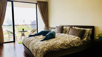 A bedroom with a large bed, a balcony with chairs, and a city view.