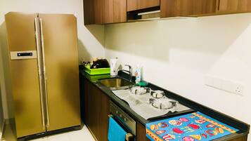 A compact kitchen with a stainless steel refrigerator, a sink, and a stove.