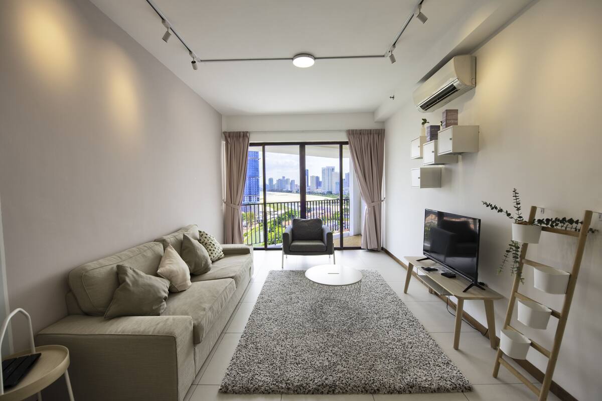 A modern living room with a sofa, a TV, a coffee table, and a balcony with a city view.