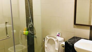 A bathroom with a glass-enclosed shower, a toilet, and a sink.